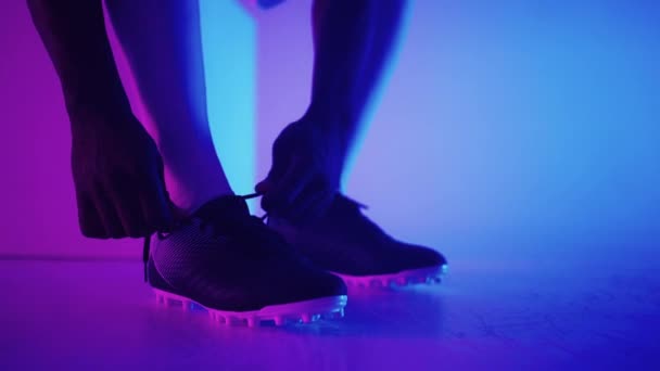 Großaufnahme eines schwarzafrikanischen Fußballers, der Schnürsenkel an Studio bindet, Zeitlupe. Fußballer schnürt seinen Schuh. Niedriger Schnitt. Fußballschuhe binden und sich auf ein Fußballspiel vorbereiten — Stockvideo