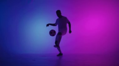 Zenci bir oyuncu karanlık bir stüdyoda, yerde neon ışıkları ve yavaş çekimde kırmızı ve mavi ışık efektleri olan bir futbol topuyla hokkabazlık yapar. Afrikalı profesyonel futbolcu