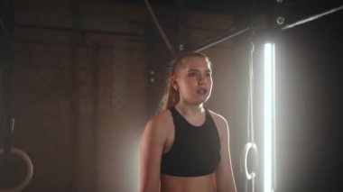 Genç bir kadın antrenmandan sonra dinleniyor ve aşağıya bakıyor. Kadın sporcu, spor salonunda spor yaptıktan sonra dinleniyor.
