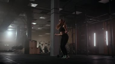 Ağır çekimde, ip atlayan genç bir kadın. Kadın spor salonunda ip atlama rutininin bir parçası. Kararlı bir kadın.