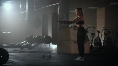 Ağır çekimde, ip atlayan genç bir kadın. Kadın spor salonunda ip atlama rutininin bir parçası. Kararlı bir kadın.