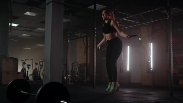 Zeitlupe: Junge Frau beim Seilspringen. Frau springt im Fitnessstudio im Rahmen ihres Workouts, zielstrebige Frau fokussiert — Stockvideo