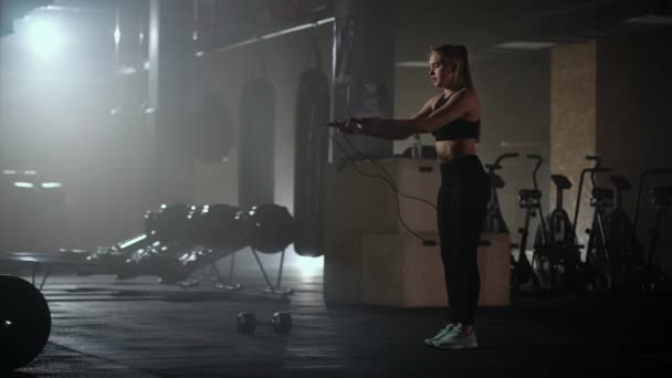 Cámara lenta: Mujer joven saltando la cuerda. mujer saltar la cuerda en el gimnasio como parte de su rutina de entrenamiento, mujer decidida enfocada — Vídeo de stock