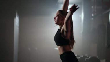 Ağır çekimde, bir kadın karanlık bir spor salonunda çalışırken kafasının üzerine bir dambıl kaldırır. Atletik güçlü kadın halterleri kaldırarak zor bir egzersiz yapıyor.