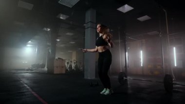 Ağır çekimde, ip atlayan genç bir kadın. Kadın spor salonunda ip atlama rutininin bir parçası. Kararlı bir kadın.