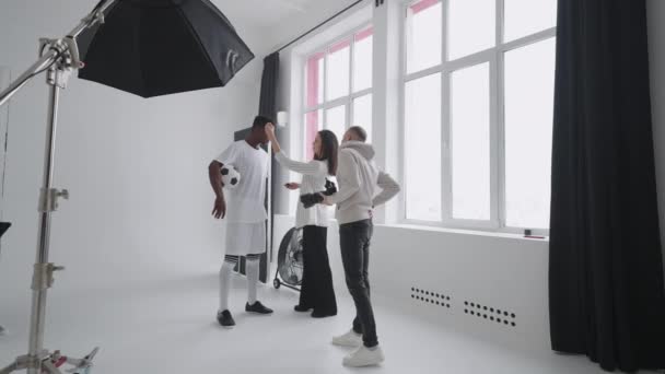 Art director checking the photos on a monitor. Professional crew team together in the studio. Behind the scene of photo shooting Professional football player and production set up in the big studio. — Stock Video