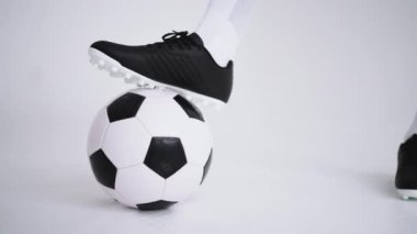 Beyaz arka planda ağır çekimde topun üzerinde duran profesyonel siyah bir futbolcunun ayağına yakın plan. Brezilyalı futbolcu poz vermek için topa bastı