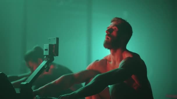 Slow motion: Man and woman training on a rowing machine in gym — Stock Video