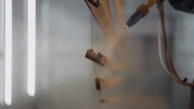 Koruyucu takım elbiseli bir adam ve maske boyacısı parçaları boyuyor. Küçük işletme boyama dükkanı. Parçaları boyamak için atölye.