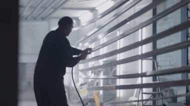 Çelik yapılar üreten adamlar boya atölyesinde boya yapmak için parça hazırlıyorlar.