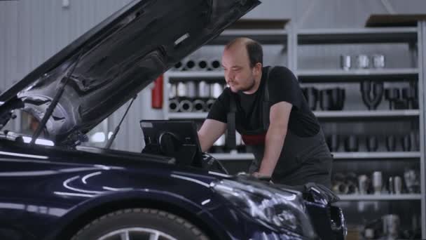 Bilmekaniker arbetar med bildiagnostikverktyg i en verkstad. Car Service Manager eller mekaniker Använder en surfplatta Dator med en futuristisk interaktiv diagnostik programvara. — Stockvideo