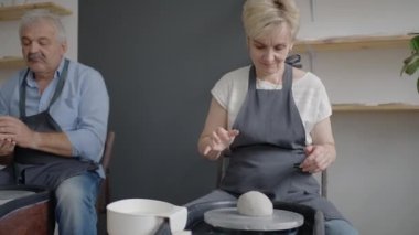 Üç yaşlı insan çömlekçi çarkında ağır çekimde çalışıyor.