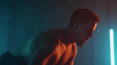 Profesyonel kaldırıcı geceleri spor salonunda tek başına antrenman yapıyor, halteri kaldırıp indiriyor.