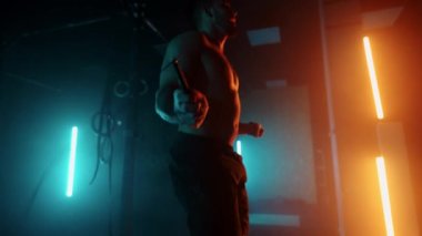 Sportif adam geceleri spor salonunda tek başına idman yapıyor. Dayanıklılık ve güç için ip atlıyor.