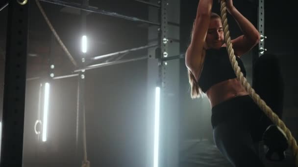 Sportovní mladá žena v černém sportovním oblečení je skákání na laně a zavěšení v tělocvičně — Stock video