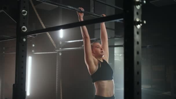 Mulher está fazendo pull-up no bar esporte no salão de ginástica, treinando sua resistência e força — Vídeo de Stock