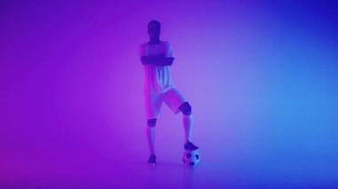 Stüdyoda topu olan profesyonel Afro-Amerikan futbolcu, kamera önünde poz veriyor, genç şampiyon.