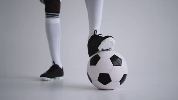 Футбольный мяч и ноги футбола в сапогах и коленных носках в студии, вид крупным планом — стоковое видео
