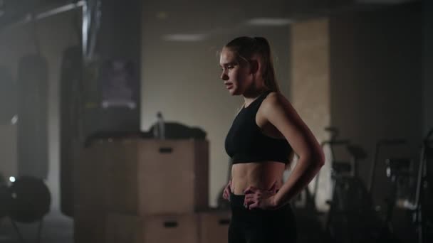 Medium portret van uitgeputte atletische vrouw in zwarte sportkleding, ademt hard en rust — Stockvideo