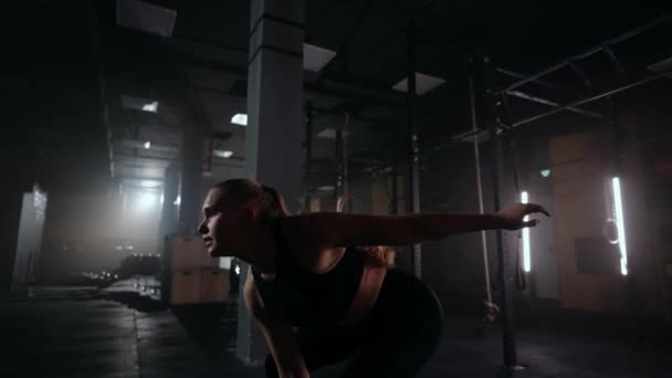 Женщина тренируется с гирями в тренажерном зале, поднимает и бросает гантели, работает в фитнес-центре — стоковое видео