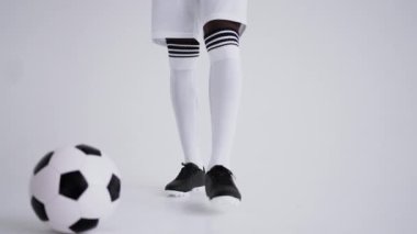 Futbol formalı siyah adam stüdyoda poz veriyor, elinde futbol topu, kendinden emin bir sporcu.
