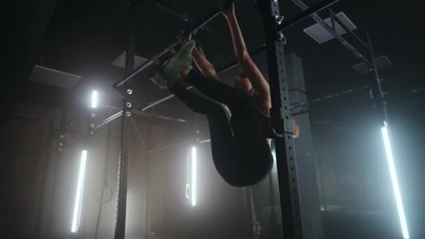 Cuerda de escalada durante el entrenamiento en el gimnasio, mujer joven está trabajando en travesaño, levantando las piernas — Vídeo de stock