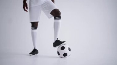 Siyah futbolcu, beyaz arkaplan ve ileri doğru portre ile stüdyoda topla poz veriyor.