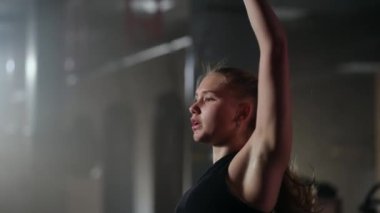 Sarışın kadın spor salonunda çalışıyor, dambılları kaldırıyor, ağır çekim, fitness merkezinde sıkı çalışıyor.