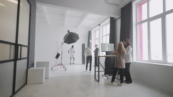 Profesjonalny zespół fotograficzny robi zdjęcia piłkarzowi w studio, afro-amerykański gracz pozował do kamery — Wideo stockowe