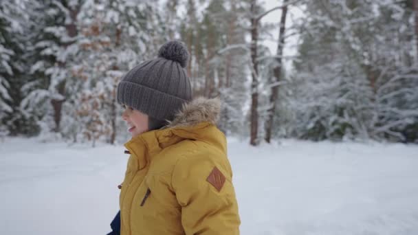 Gelukkig klein kind speelt in de winter bos, leuke jongen met warme hoed en jas loopt in het park — Stockvideo