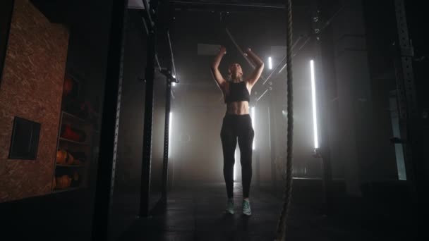 Joven mujer deportiva está entrenando en el travesaño en el gimnasio, cambiando y levantando su peso por los brazos — Vídeo de stock
