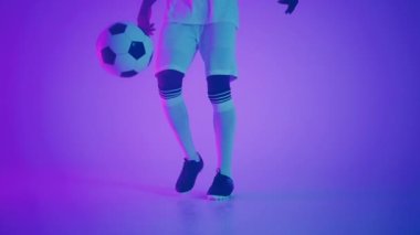 Genç Afrikalı futbolcu, atölyede top sürüyor ve ayak hareketlerini yakından takip ediyor.