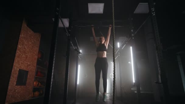 Atletisk kvinna gör pull-up på ribban i gymmet, slow motion skott av svängande kvinnlig kropp — Stockvideo
