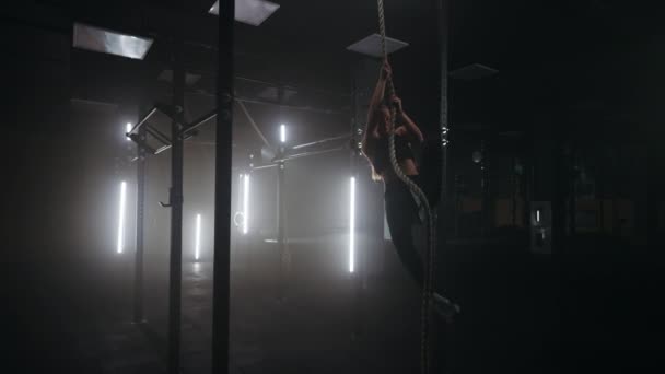 Kvinna klättrar rep i gym, träning ensam i mörk tom fitness hall på kvällen — Stockvideo
