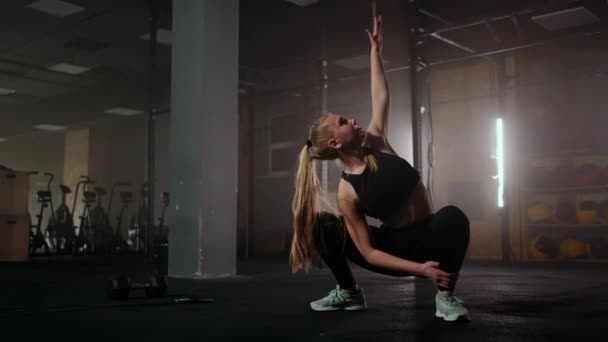 Jong blond vrouw is het doen van sport in fitness centrum, kraken en het uitstrekken van handen omhoog — Stockvideo