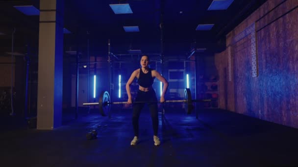 Female powerlifter is training in gym alone in night, lifting heavy barbell, tensing muscles of arms — Stock Video