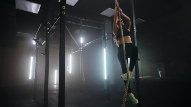 Vacker smal kvinna gör sport motion i gym, klättring rep i fitness hall — Stockvideo