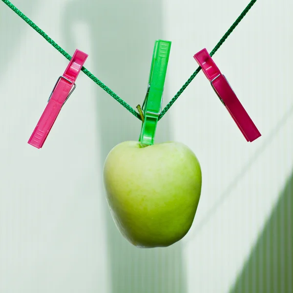 Manzana verde colgando de la cuerda con pinzas de ropa — Foto de Stock