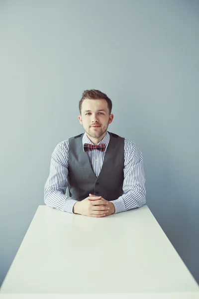 Młody biznes człowiek siedzi przy stole w kamizelce — Zdjęcie stockowe