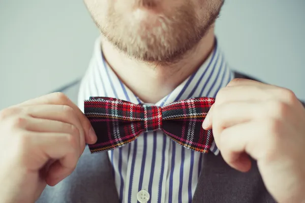 Fashion photo of a man with beard correcting his bowtie — Stock Photo, Image