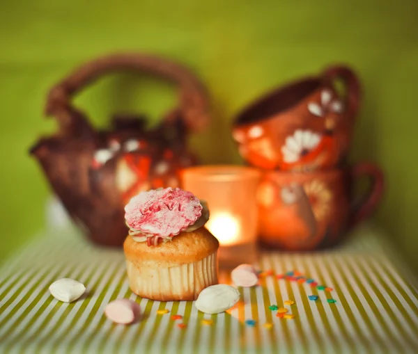 Cupcake on green background with tea pot and cups — Stock Photo, Image