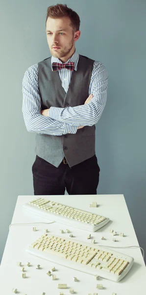 Jeune homme près de la table avec claviers d'ordinateur — Photo