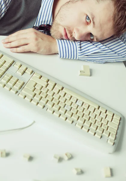 Jeune homme couché sur la table avec clavier d'ordinateur — Photo