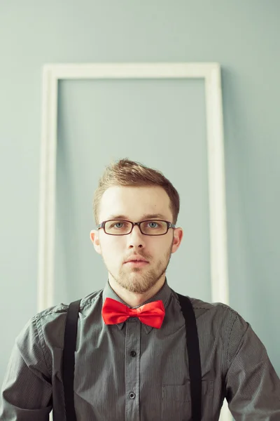 Jeune homme en lunettes, nœud papillon rouge et bretelles — Photo