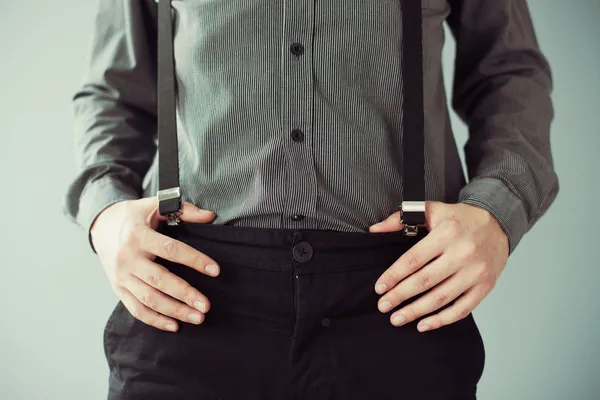 Men's hands holding pants with suspenders — Stock Photo, Image