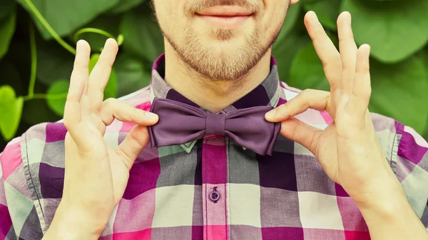 Young man in shirt correcting bowtie — Stock Photo, Image