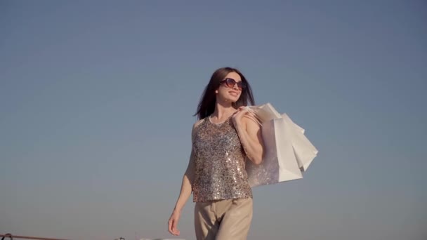 Havalı kız alışveriş torbalarıyla dışarı çıkıyor. — Stok video