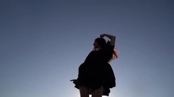 Linda silhueta menina dançando contra o céu ao pôr do sol — Vídeo de Stock