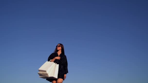 Menina de luxo em vestido preto indo ao ar livre com sacos de compras — Vídeo de Stock