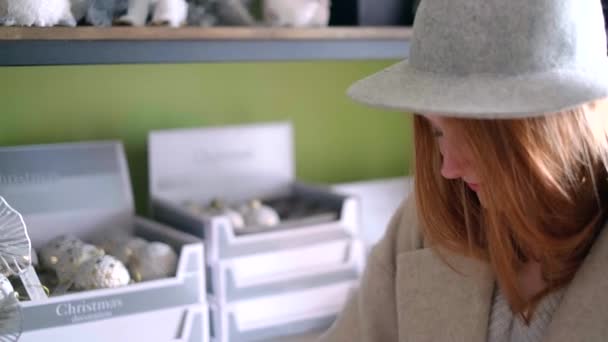 Mädchen mit Hut wählt Weihnachtsdekoration im Supermarkt — Stockvideo